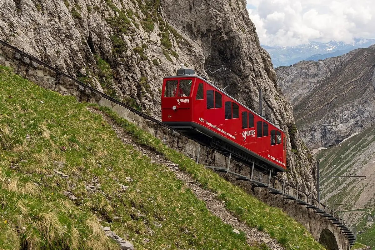 Red Pilatus cogwheel train climbing the rocky mountain route in summer