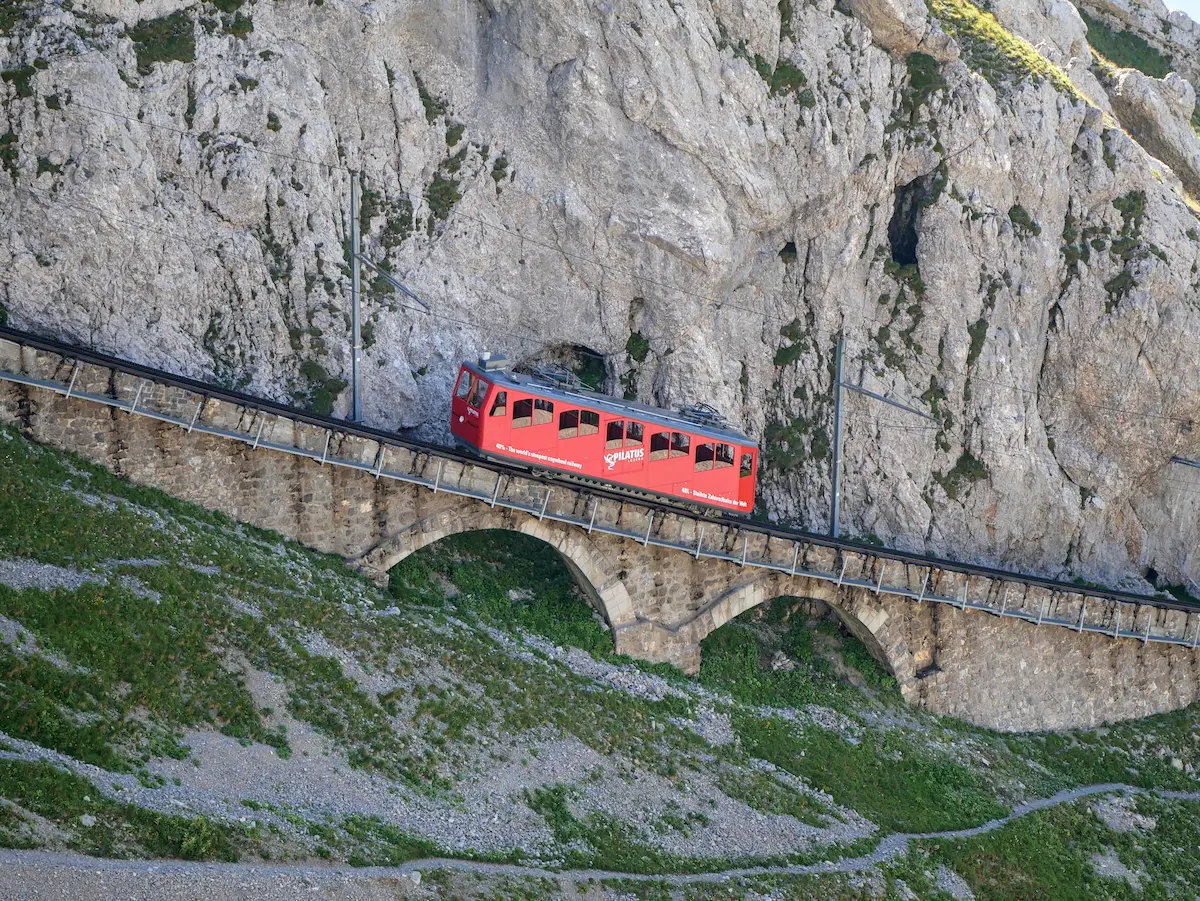 Red Pilatus cogwheel railcar descending below Pilatus Kulm