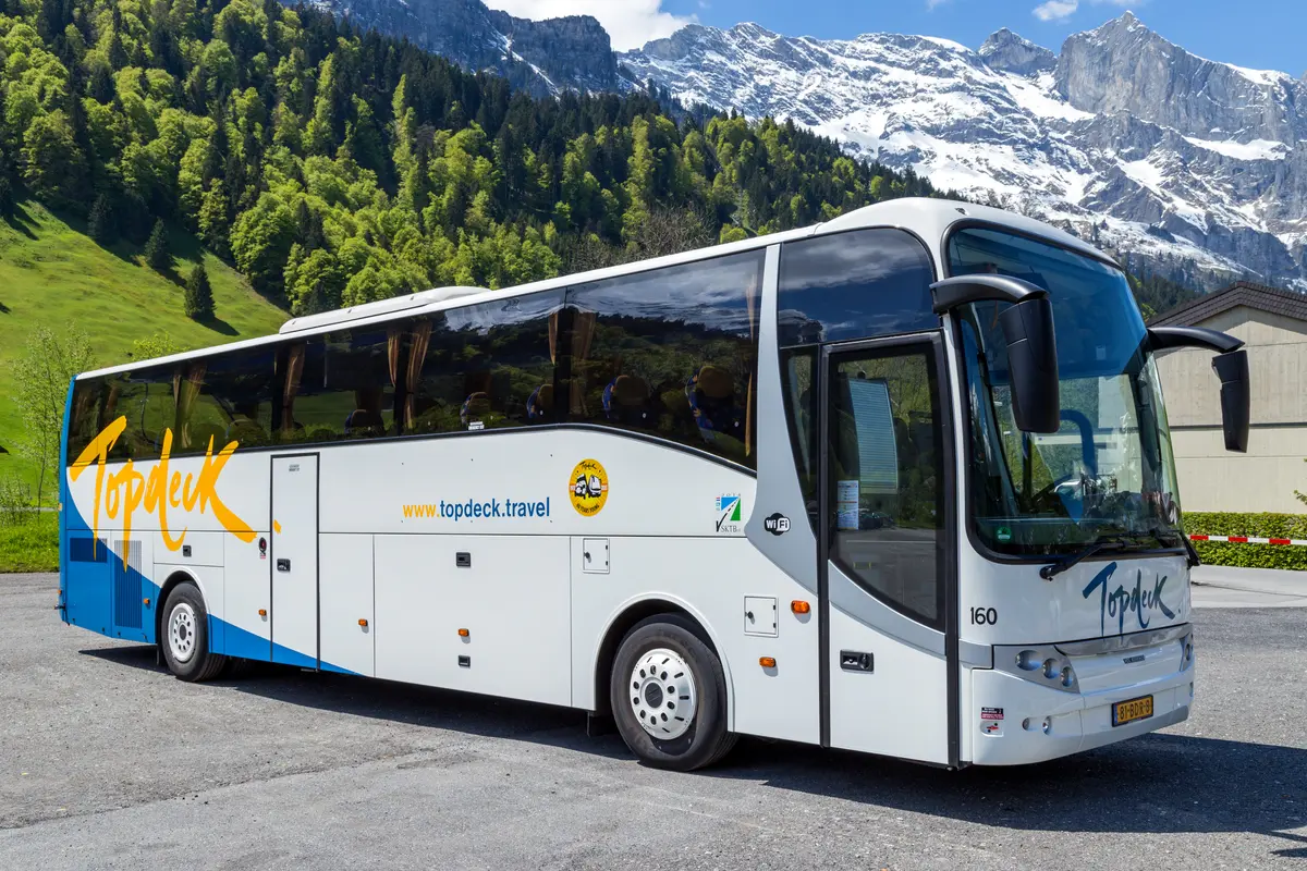 Coach parked in Engelberg beneath snow-covered peaks, illustrating the guided Mount Titlis transport option