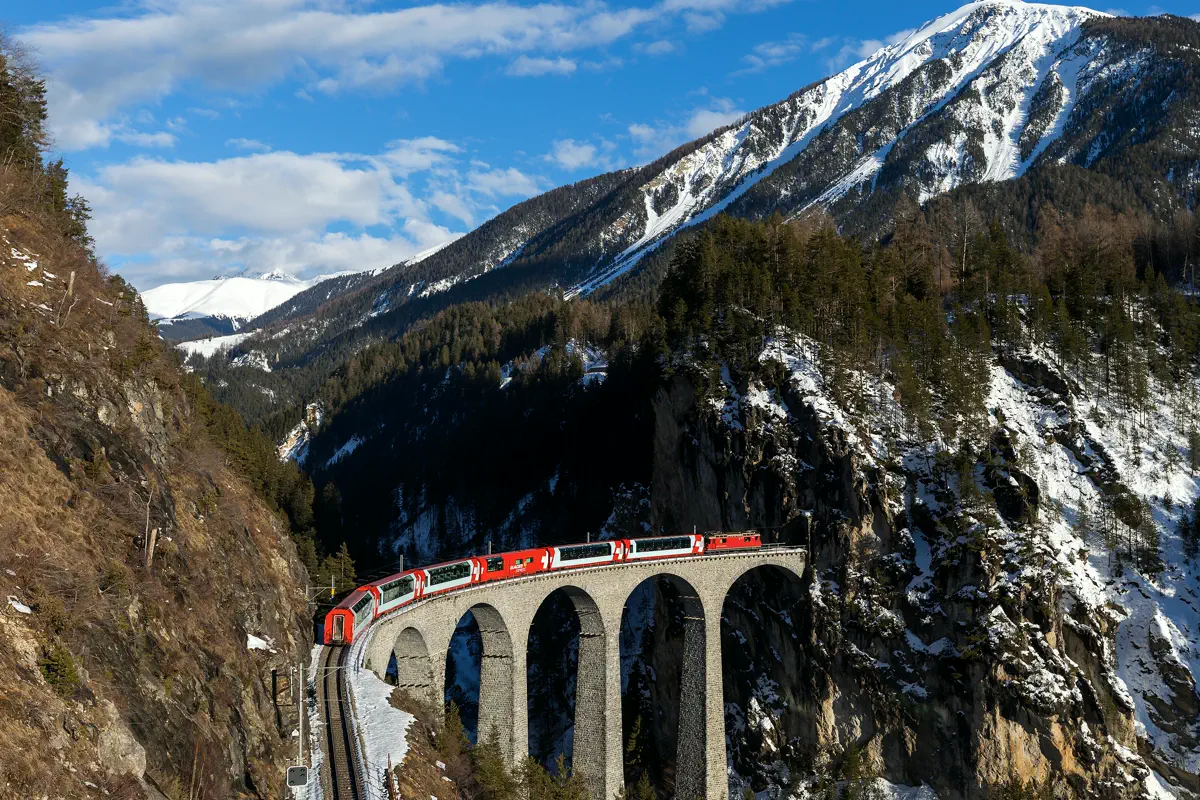 Red Rhaetian Railway panorama train crossing the Landwasser Viaduct, the kind of long intercity leg that decides whether a Swiss rail pass pays off