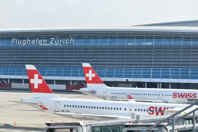 Two SWISS aircraft parked at the terminal below the Flughafen Zürich sign at Zurich Airport
