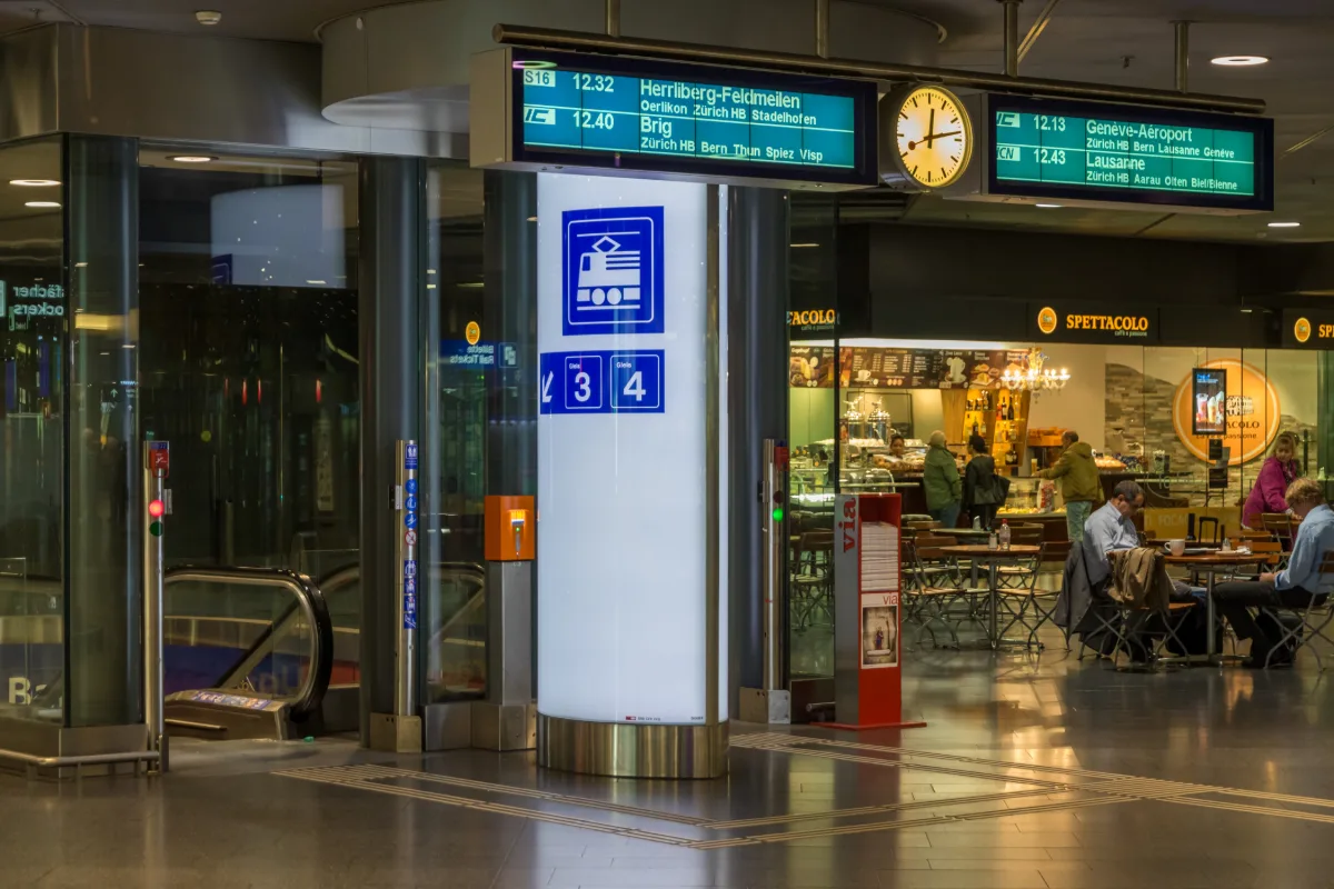 Blue railway sign and escalator down to the tracks inside Zurich Airport