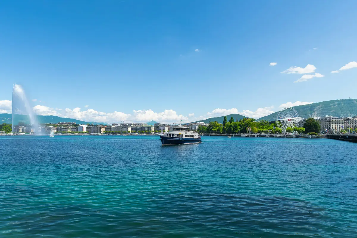 Passenger boat crossing Lake Geneva with the city and Jet d’Eau behind
