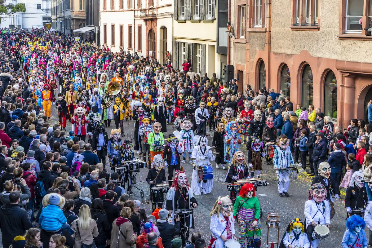 AI-generated daytime illustration of masked carnival participants and musicians in a Basel street procession.