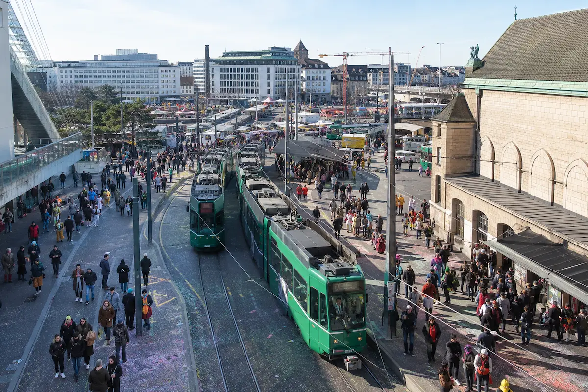 AI-generated daytime illustration of tram travel and crowds during Basel Carnival.